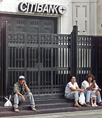 Ciudadanos argentinos descansan en la puerta de un banco en Buenos Aires.