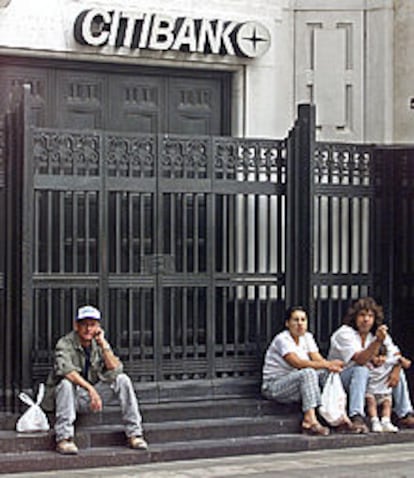 Ciudadanos argentinos descansan en la puerta de un banco en Buenos Aires.