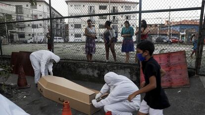 Funcionários de uma funerária levam de uma favela no Rio de Janeiro o cadáver que, segundo a vizinhança, levou 30 horas para ser recolhido.