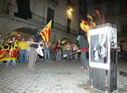 Dos encapuchados queman una foto de los Reyes frente al Ayuntamiento de Girona el jueves.