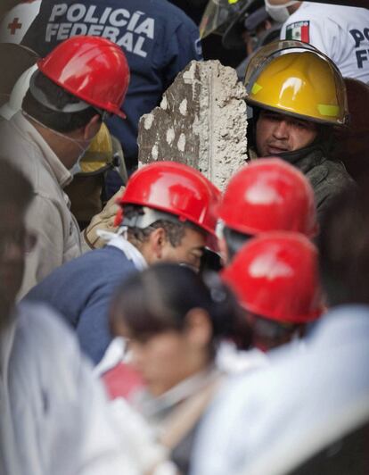 Un bombero retira un cascote de cemento en la sede de Pemex.