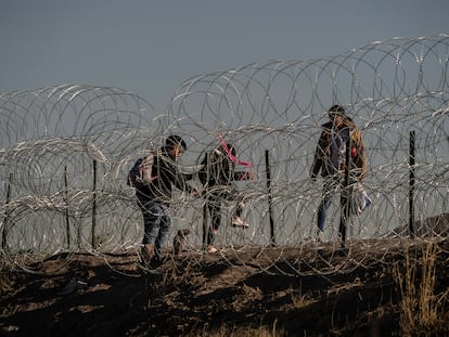 Tres migrantes cruzan el alambrado en la frontera entre México y EE UU en Ciudad Juárezm el pasado 10 de mayo.