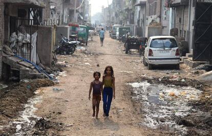 Niños indios caminan por una calle repleta de basura, en Nueva Delhi (India).