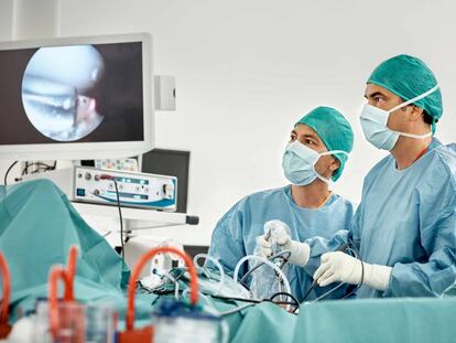 Cirujanos observan un monitor durante una intervención de rodilla. 