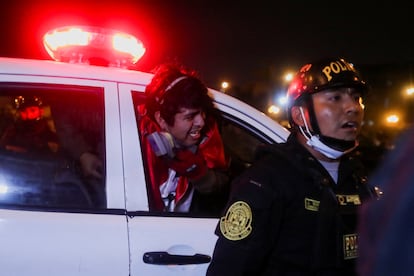 Un manifestante detenido asoma la cabeza por la ventana del vehículo policial.