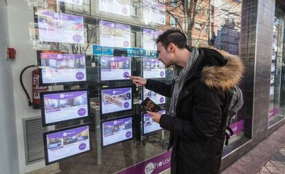 Un joven observa el escaparate de una inmobiliaria en Madrid. 