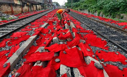 Un hombre coloca pieles de res teñidas sobre vías de ferrocarril para secarlas, en Calcuta (India).