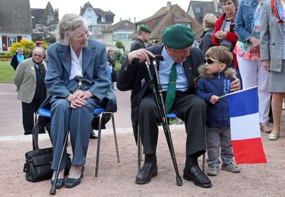 El veterano de guerra Leon Gautier conversa con un ni&ntilde;o que sostiente la bandera francesa durante el homenaje en recuerdo del desembarco. 