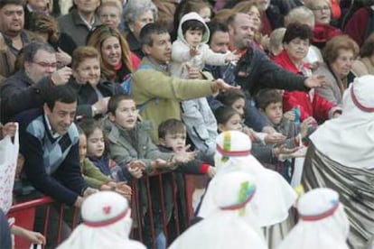 Los sevillanos piden a los Reyes Magos caramelos al paso de la cabalgata.