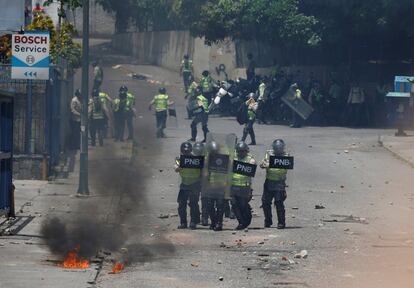 Miembros de la policía se protegen de objetos lanzados por los manifestantes, en Caracas.