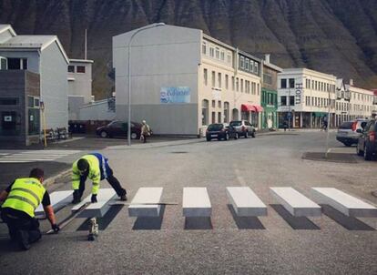Dos operarios pintan un paso de cebra tridimensional en Ísafjörður (Islandia).