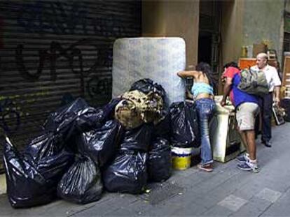 Bolsas de basura, un colchón y muebles, en un tramo de la calle de Sant Pau.