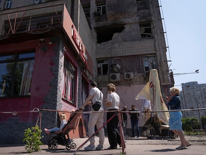 Vecinos de Kiev paseaban este domingo junto a un edificio alcanzado por el bombardeo ruso de la madrugada.