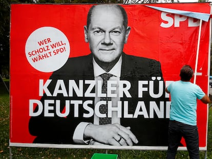 Un hombre pegaba el lunes en Bonn un cartel del candidato del SPD alemán, Olaf Scholz.