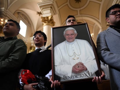 Un feligrés de Bogotá (Colombia) sostiene una fotografía del papa Benedicto XVI durante sus funerales, a comienzo de este 2023.