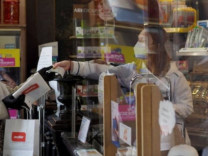 Una persona es atendida por una trabajadora de una farmacia de Vitoria durante el estado de alarma por la crisis del Covid-19.