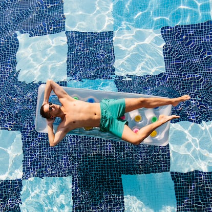 Un hombre en una colchoneta dentro de una piscina.