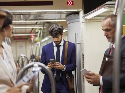 Un grupo de personas utilizando sus teléfonos móviles en un tren de Cercanías.