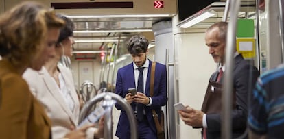 Pasajeros mirando sus teléfonos móviles en un tren de Cercanías.