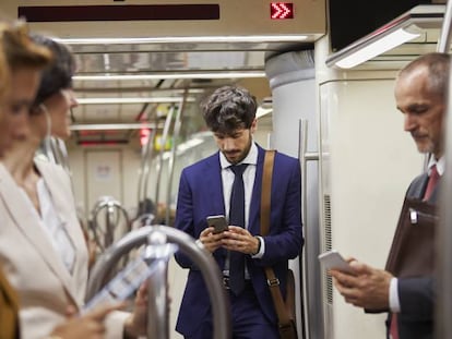 Pasajeros mirando sus teléfonos móviles en un tren de Cercanías.