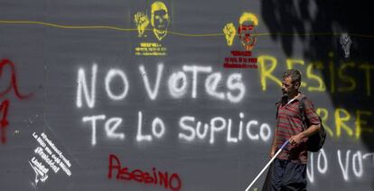 Un hombre pasa al lado de un cartel contra la votación de este domingo.