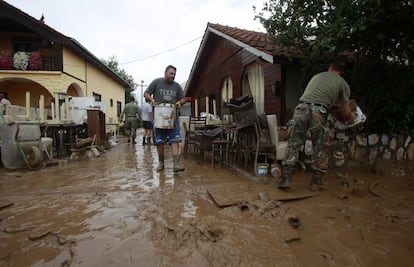 Soldados ayudan a los residentes a tirar cubos de barro desde sus casas inundadas, en la localidad de Stajkovci, cerca de Skopie.
