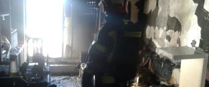 Un bombero inspecciona el salón de la vivienda incendiada.