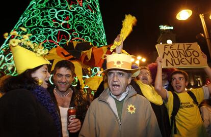 Celebración de bienvenida al 2012 en la Puerta del Sol de Madrid. En el centro de la imagen, un hombre tocado con un sombrero con un signo del 15-M, el movimiento de protesta política que protagonizó el 2011 en España.