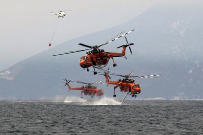 Helicópteros recogen agua para luchar contra los incendios en la isla de Evia, en Grecia.