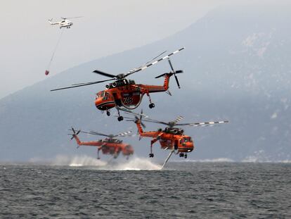 Helicópteros recogen agua para luchar contra los incendios en la isla de Evia, en Grecia.