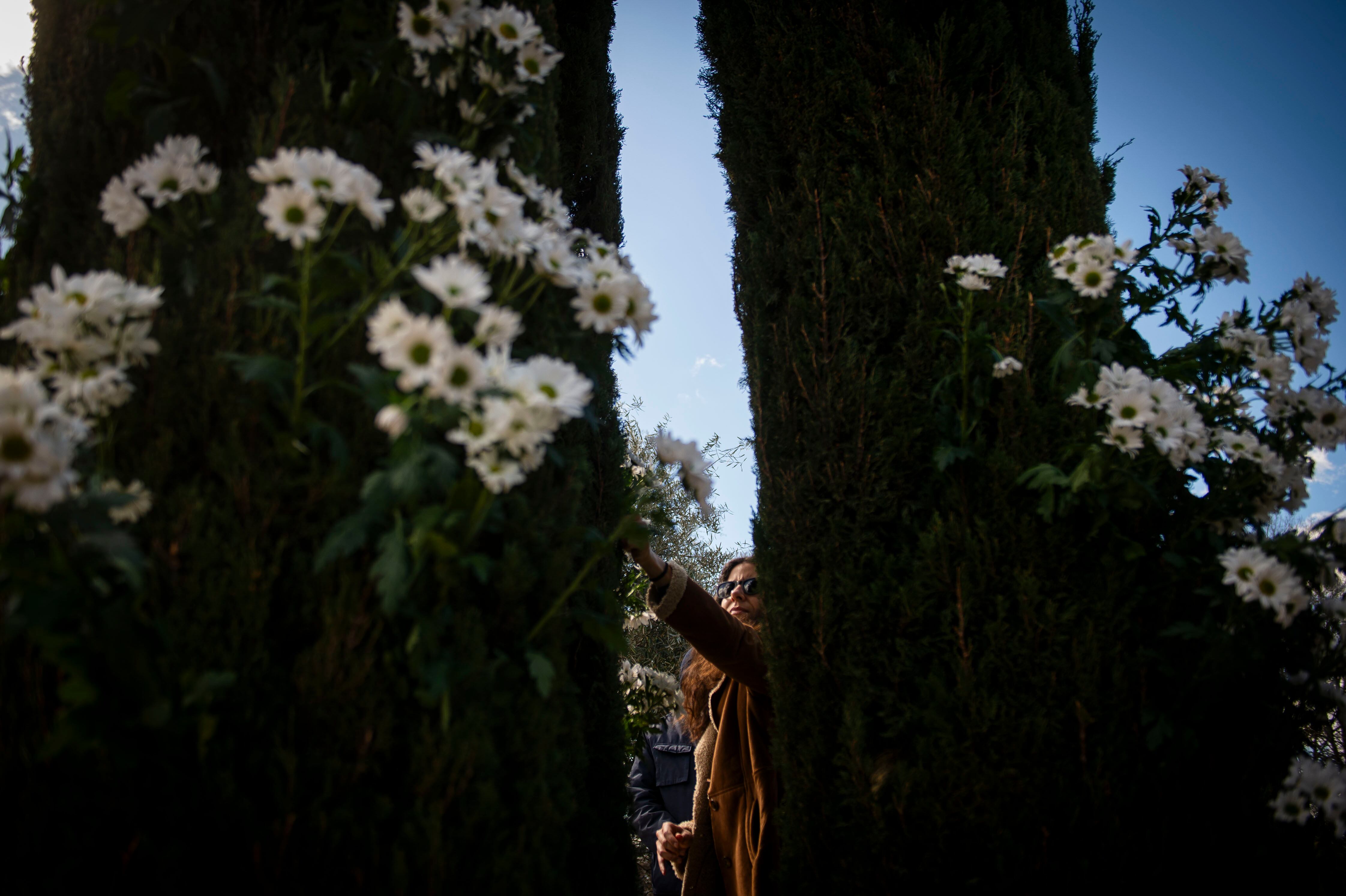 Una mujer coloca flores blancas durante el aniversario de los 20 años de los atentados terroristas en Madrid, este lunes en el parque de El Retiro.