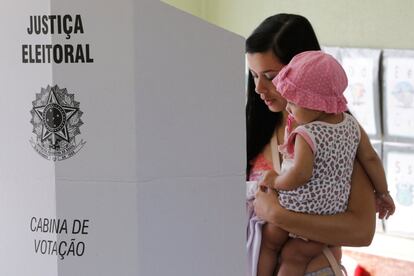 Uma mulher vota com seu bebê em Brasília. 