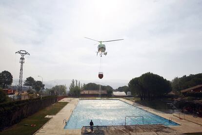 Un helicóptero toma agua en una piscina para lanzarla sobre el fuego.