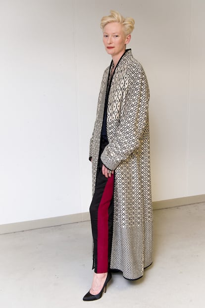 Tilda Swinton ha confiado esta semana en uno de sus diseñadores favoritos, Haider Ackermann. Fiel a su estilo masculino, la actriz se ha decantado por un abrigo estampado de la colección de hombre del diseñador. Complemento perfecto para el look informal de camisa negra y pantalón de pinzas con una franja roja en su lateral.