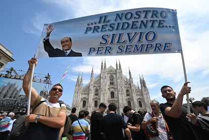 Dos personas sostienen una pancarta con el lema 'Nuestro presidente, Silvio para siempre' frente al Duomo de Milán.