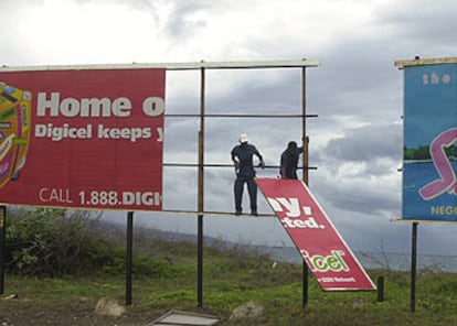 Dos trabajadores retiran las vallas publicitarias en Kingston, Jamaica, para evitar accidentes a causa del <i>Charley</i>.