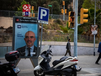 Varias perosnas pasean a la salida del metro Torre Baró Vallbona junto a carteles de candidatos a las elecciones del 28M.
