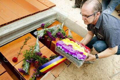 Un hombre deposita adornos florales con los colores de la bandera republicana sobre los restos mortales de los 28 fusilados el 25 de abril de 1939 en Alcaudete de la Jara (Toledo), que hoy han sido reinhumados en el cementerio del pueblo en una sepultura única.