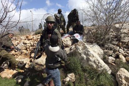 Un soldado israelí empuja a un niño palestino durante los enfrentamientos en Beit Omar, cerca de Hebrón, en Cisjordania, el día 17 de marzo de 2012.