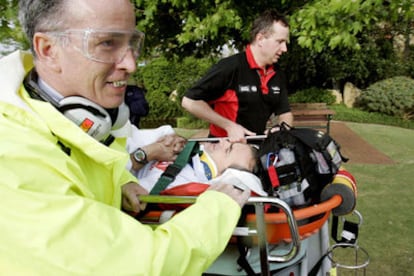 Dos miembors d elos servicios de emergencia evacuan en camilla a Carlos Sainz del circuito del Rally de Australia.