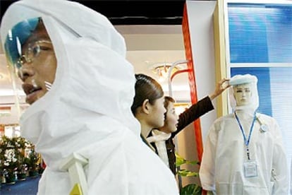 Dos jóvenes chinas tocan una máscara de protección contra el SARS en una exposición en Guangzhou, capital de Cantón.
