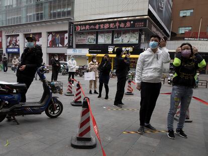 Residentes de Wuhan guardan cola para entrar en un supermercado.