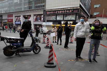 Residentes de Wuhan guardan cola para entrar en un supermercado.