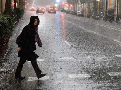 Una persona cruza una calle en pleno aguacero, ayer en el centro de Barcelona.