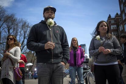 Aaron Jasper (i) y Jackie Pickering, llevan flores a la entrada de la calle Boylston cerca de la línea de meta del Maratón de Boston, en señal de respeto a las víctimas del atentado que mató a tres personas.