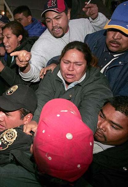 Familiares de los mineros forcejean con los policías tras el anuncio de la suspensión del rescate.