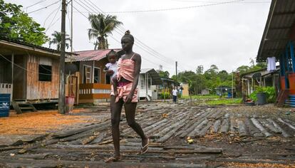 Una mujer camina con su bebé en brazos por una calle de Isla Mono, en el departamento colombiano de Chocó, el 23 de abril de 2019.