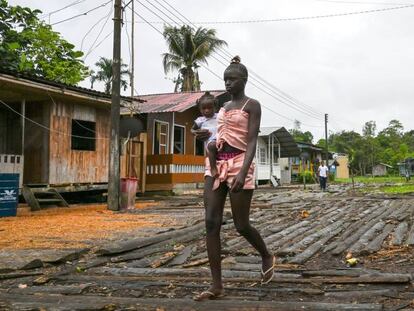 Una mujer camina con su bebé en brazos por una calle de Isla Mono, en el departamento colombiano de Chocó, el 23 de abril de 2019.