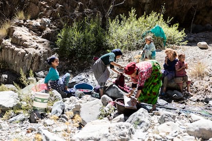 Un grupo de mujeres y niñas lavan en el río la ropa que han conseguido recuperar de entre los escombros.