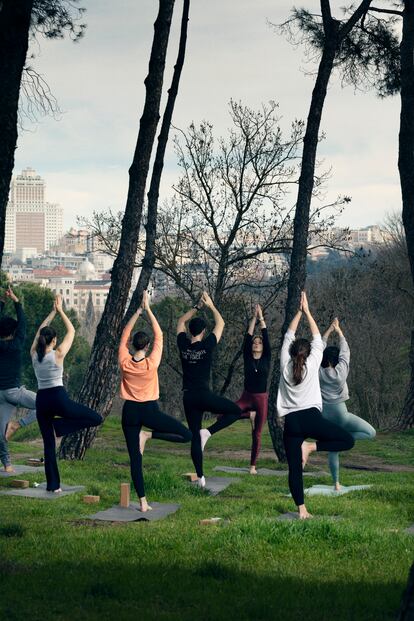 Iva Gigovski, y de espaldas, sus alumnos de yoga, en la Casa de Campo.